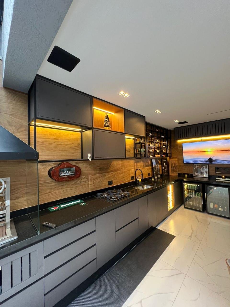 Casa Vila Carrão 02: Área gourmet com marcenaria em tons de cinza, madeira e iluminação cênica.