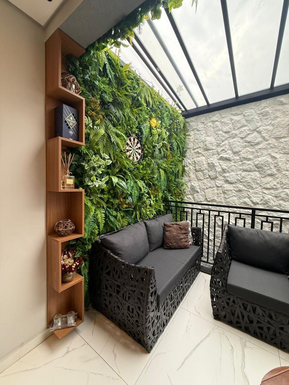 Varanda com jardim vertical, estante e poltronas